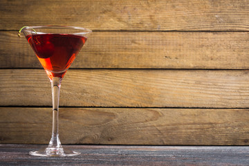 Red cocktail with cherry on the wooden background