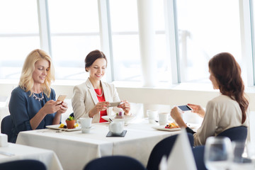 women with smartphones taking picture of food