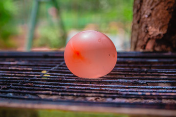 Balloon filled with water placed on a hot grill. An experiment that tests what would be the...