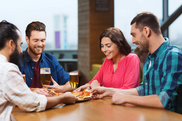 friends eating pizza with beer at restaurant