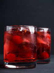 Red cocktail with cherry on the wooden background