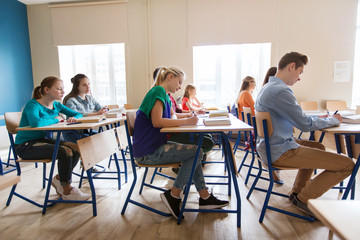 group of students with books writing school test