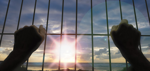 Hands of the prisoner, want freedom, sunset in background
