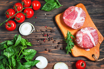 Ingredients for making homemade burger on wooden cutting board.