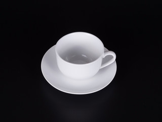 White cup on a saucer isolated on a black background