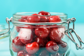 Jar Of Red Fresh Cherries On Turquoise Background
