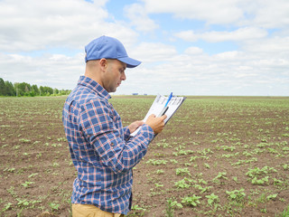 Farmer in plaid shirt controlled his field and writing notes - 113903299