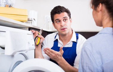 Obraz premium Repairman explaining woman how to use washer