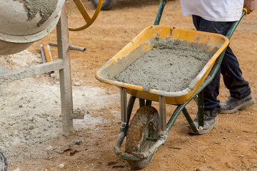 Builder is carrying a wheelbarrow with mortar to fill the foundations of a wall