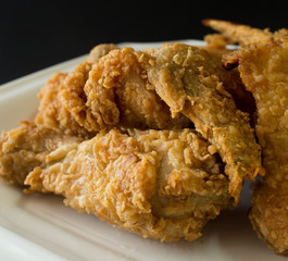 fired chicken on a white plate and black background