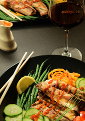 Fried Meat Ribs with Beans, Sliced Cucumber and Tomato in Big Black Plate. Red Wine Glass.