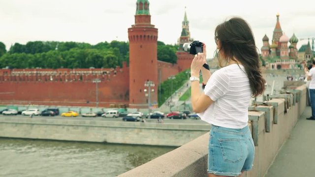 Beautiful young caucasian brunette girl taking photos of Moscow Kremlin