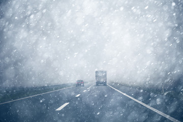 Car overtaking a truck on a heavy snowy, rainy and slippery highway. Dangerous overtaking at bad weather condition. - obrazy, fototapety, plakaty