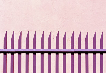 Pink metal fence and plaster wall.