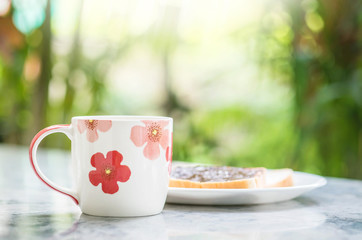 Closeup cute cup on blurred marble desk and garden view in the morning textured background