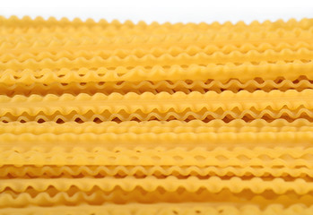 Uncooked Italian pasta mafaldine on a white