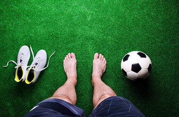 Barefoot football player against green grass, studio shot © Halfpoint