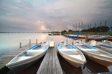 boats and yachts by pier during showery sunset