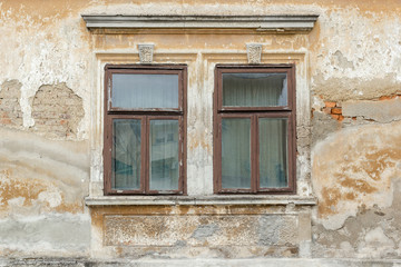 Two old broken windows on an abandoned old building