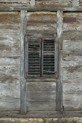 Old wooden window with wooden blinds on an abandoned wooden house