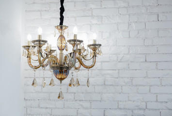 Glass chandelier against a white wall from a brick