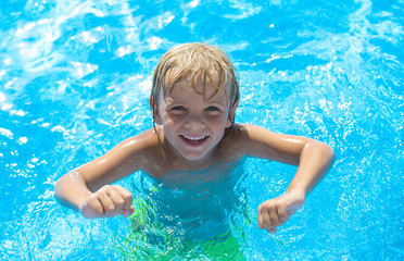 Smiling little boy has fun in swimming pool