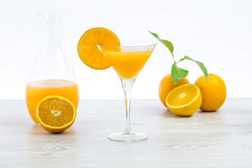 oranges and glass of juice on a wooden table and white background
