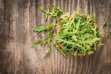 Fresh green arugula in bowl on wooden table