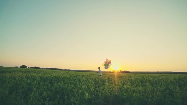 Litle boy with balloons at sunset. RAW video record.