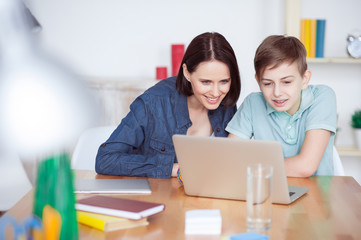 Happy mother helping his son to do homework