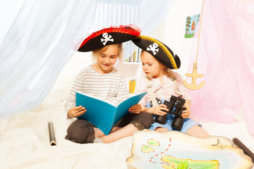 Two girls in pirate's costumes reading fairy-tale