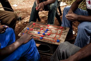 Group of men sitting outdoors, playing Morabaraba in South Africa