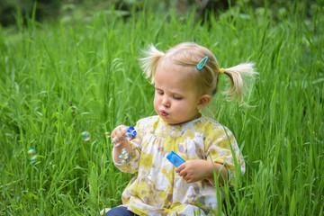 Beautiful baby girl blowing soap bubbles in the park