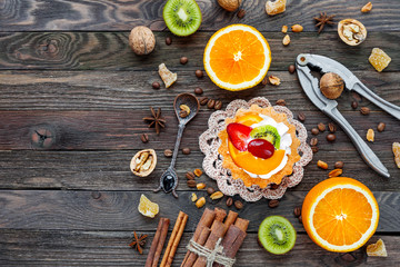 Rustic wooden background with fruit tart, spices, kiwi and oranges. Top view, flat lay. Place for text.