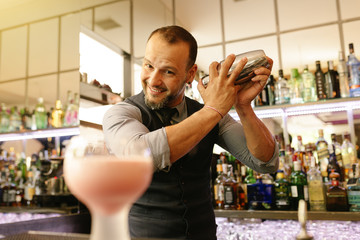 Barman is making cocktail at night club.