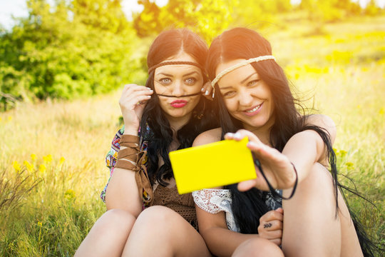 Two boho fashion sisters taking a selfie on smartphone