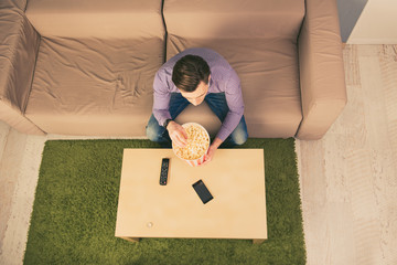 Top view of young man resting at home while watching film and ea