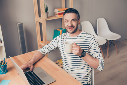 Happy smiling man working with laptop and drinking coffee