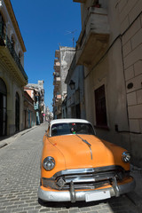 Fototapeta na wymiar Orange american car parked in Old Havana under a blue sky