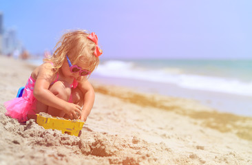 Fototapeta na wymiar cute little girl play with sand on beach