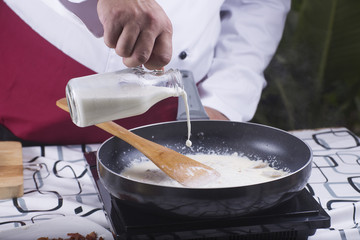 Chef pouring fresh milk to the pan