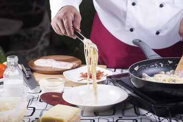 Chef putting Spaghetti carbonara to the plate with tongs