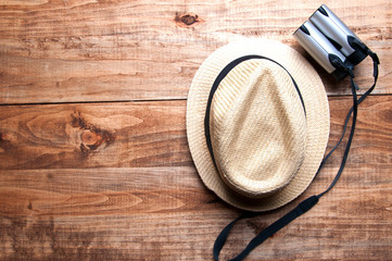 Summer hat and binocular in the middle on the wooden background