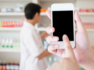 women using smart phone in pharmacy blurred background