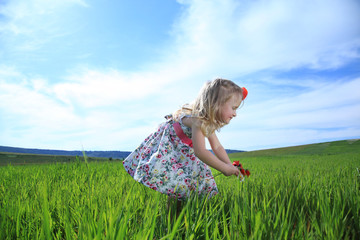 Little girl on background of clouds in green field warm day