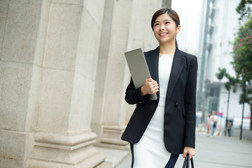 Young Businesswoman holding laptop computer and walking outside