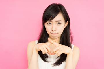 手でバツを作る女性