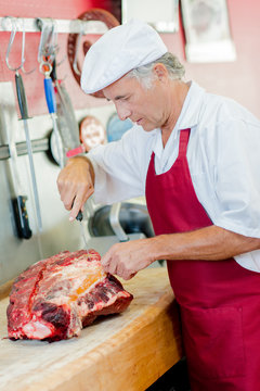 Butcher working on a large cut of beef