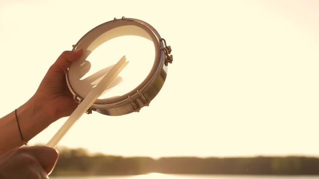 игра на музыкальном инструменте тамбурин на фоне неба в закате 