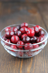 Sweet cherry in glass bowl on the wooden table.
